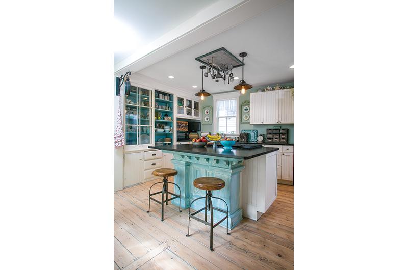 Old, new, and blue: The built-in, glass-fronted cabinets are original to the cottage, while the blue pedestal (a former altar) was found in an antique store.