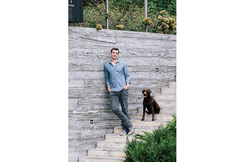 Architect Aaron Schiller and his chocolate Labrador, Squibby, on the steps of the family home he designed in Chilmark.