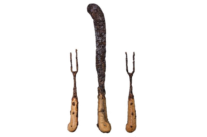 Artifacts found at the site included various utensil fragments such as two-tined forks and a knife with a pistol-grip handle.