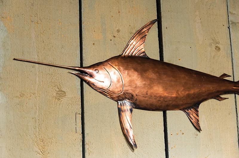 Finished pieces, such as this swordfish, hang at The Copperworks gallery in Menemsha.